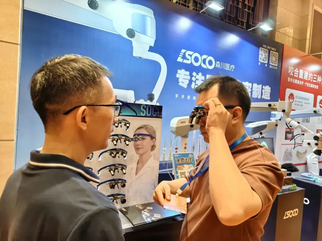 Dentists testing a SOCO dental operating microscope and dental loupes at the implant congress booth